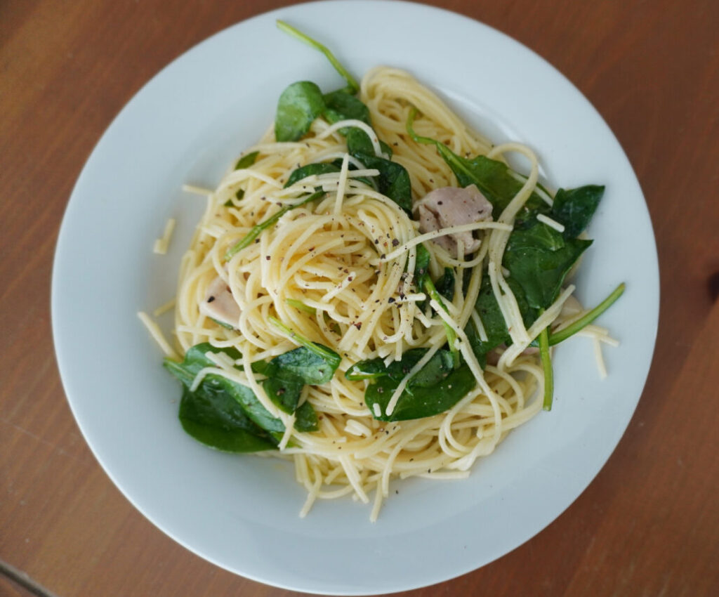 white plate of lemon chicken pasta on a wooden table