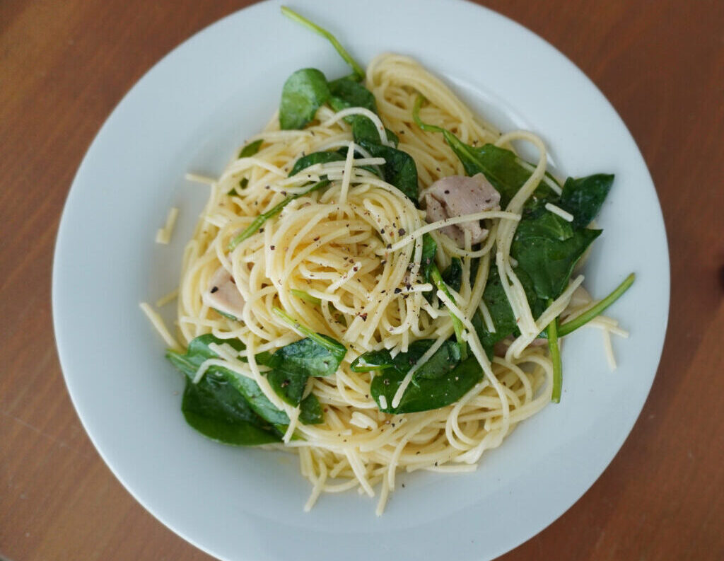 white plate of lemon chicken pasta on a wooden table