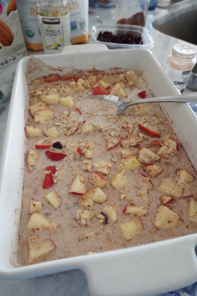 dry ingredients for baked apple cinnamon oatmeal mixed with milk in a baking dish