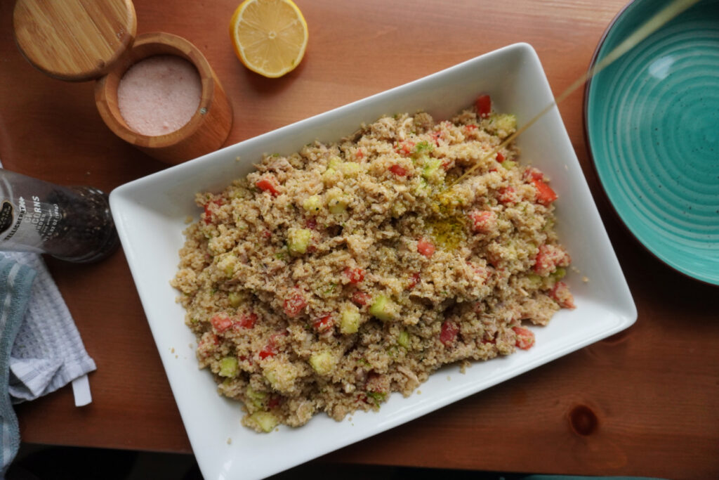 Mediterranean quinoa salad with chicken being drizzled with olive oil