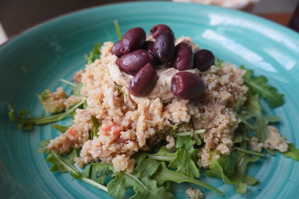 Mediterranean quinoa salad with olives and hummus on top