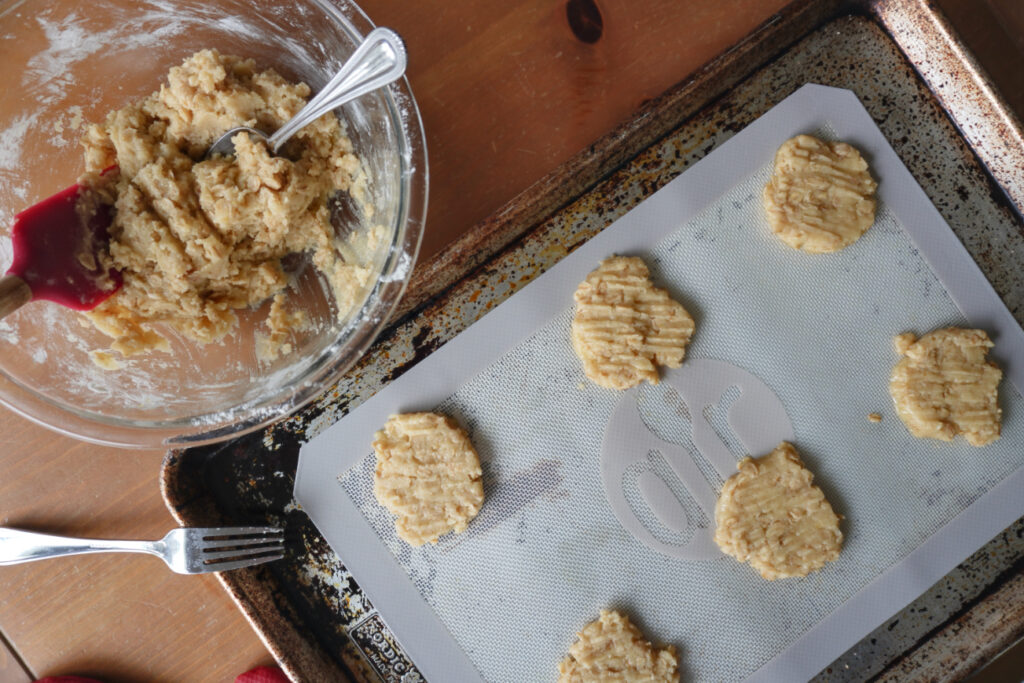 baking sheet of cookie dough balls flattened with a fork