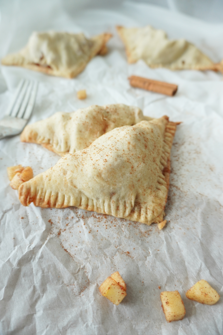 apple turnovers sprinkled with cinnamon on white parchment paper