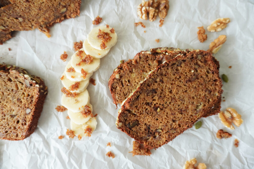 stacked sliced of banana bread arranged with slices of banana and brown sugar