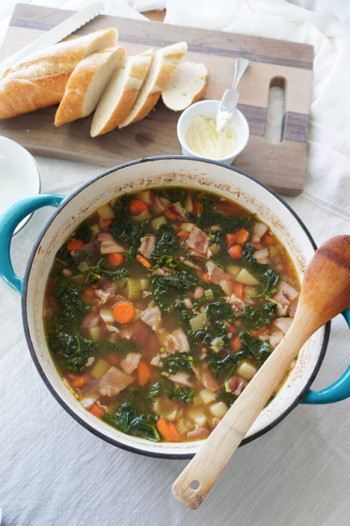 pot of black eyed pea vegetable soup with a cutting board of sliced bread and butter