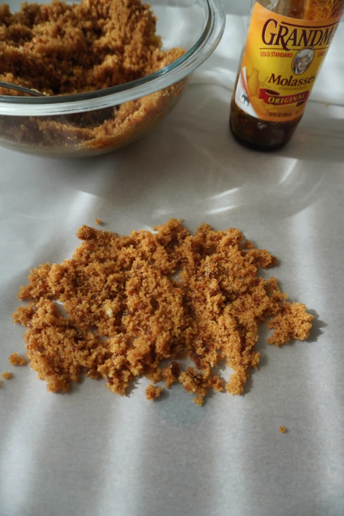 brown sugar on parchment paper with a jar of molasses and bowl of brown sugar behind it