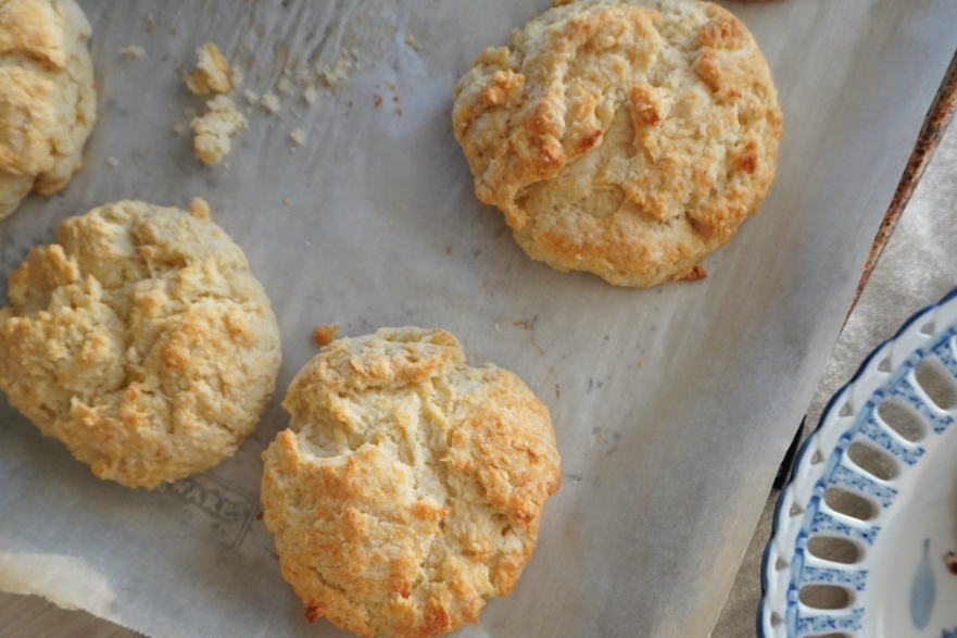 Three buttery biscuits in the corner of a baking sheet
