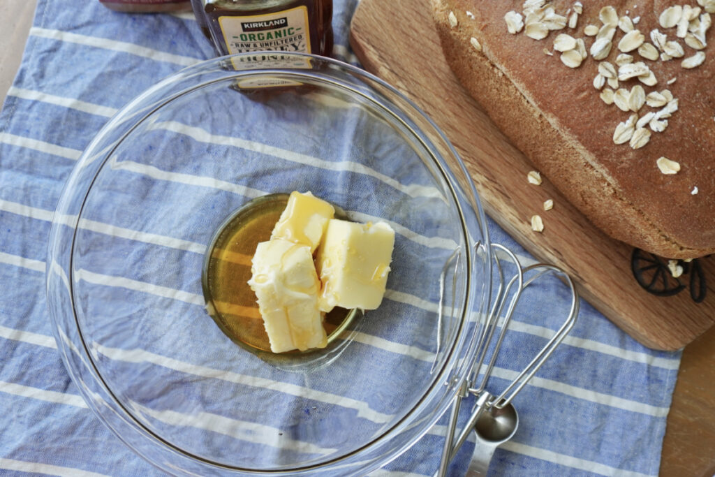 a stick of butter and honey in a mixing bowl on a blue tea towel