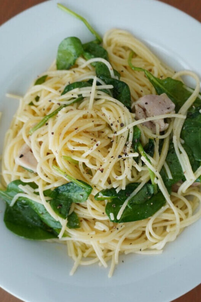 white plate of lemon chicken pasta on a wooden table